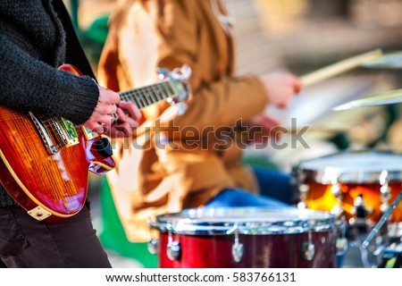 Festival music band. Hands playing on percussion instruments in city park . Drums with sticks closeup. Body part of male musicians. Sharpen is guitar and man hand.