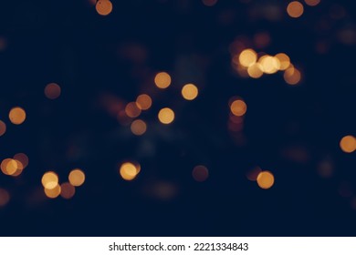 Festive abstract defocused Background with bokeh lights, photographic effect. Golden Christmas light spots on dark blue background, defocused. Beautiful Blurred Holiday Texture for design