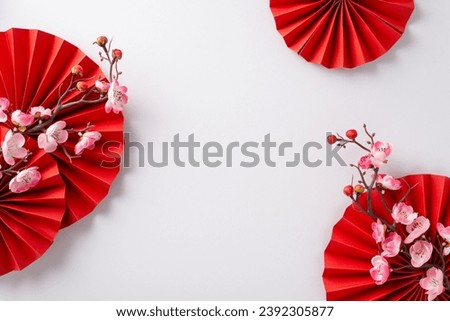 Festive arrangement for Lunar New Year, featuring red fans, and pink sakura flowers. Top view on a white background with ample space for custom messages or advertisements