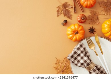 Festive autumn table setting idea. Top view shot of plate, cutlery, pumpkins, dry leaves, checkered napkin, anise, cinnamon sticks, acorns on pastel brown background with blank space for ads or text - Powered by Shutterstock