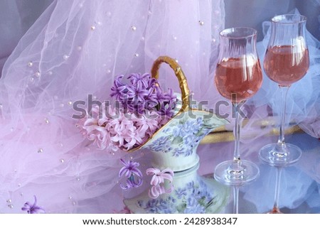 Festive background, still life in purple shades, spring flowers in a vase and two glasses of pink wine. Antique porcelain basket, hyacinths, birthday, mother's day, copy space