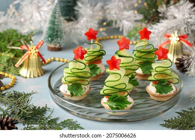 Festive canapes in the shaped of Christmas trees made of cucumbers on a light blue background - Shutterstock ID 2075006626