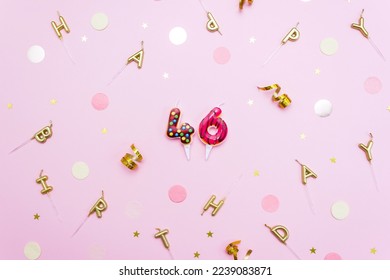 Festive candles figures in the shape of sweet donuts on a pink background surrounded by confetti. Concept of celebrating 46 years. Selective focus