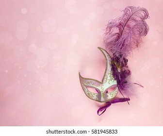 Festive Carnival Background with masks with feathers and copy space. Carnival mask on a pink background. 