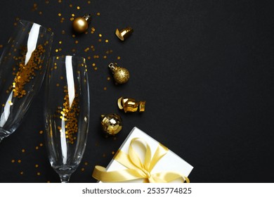 Festive Christmas background with champagne glasses, gift box,  different decorations, balls and confetti on black background  - Powered by Shutterstock