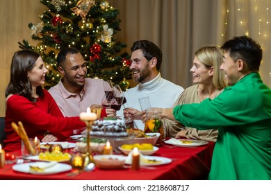 Festive Christmas dinner, diverse friends celebrating new year at home, eating and drinking wine, smiling and wishing each other happy holidays. - Powered by Shutterstock