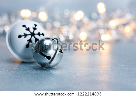 festive christmas jingle bells on grey background with blurred garland lights. macro view