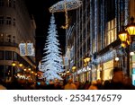 Festive Christmas lights on a busy Budapest shopping street at night 