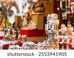 Festive Christmas market stall displaying nutcrackers, Santa figures, wreaths, and other holiday decorations. The vibrant display creates cheerful and traditional holiday atmosphere