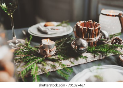 Festive Christmas and New Year table setting in scandinavian style with rustic handmade details in natural and white tones. Dining place decorated with pine cones, branches and candles - Powered by Shutterstock