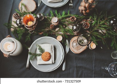 Festive Christmas And New Year Table Setting In Scandinavian Style With Rustic Handmade Details In Natural And White Tones. Dining Place Decorated With Pine Cones, Branches And Candles