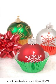 Festive Christmas Ornaments Placed In Cupcake Liners With Snow And A Bow