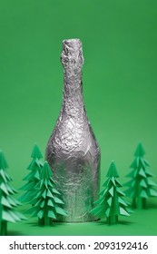 Festive Christmas Scene With Champagne Bottle And Green Origami Fir Tree. New Year And Christmas Card On A Green Background. New Year Background With Paper Fir Tree.