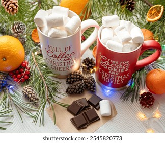 Festive Christmas scene with two mugs of hot chocolate topped with marshmallows, surrounded by pine branches, pinecones, oranges, chocolate, and holiday decorations, creating a cozy holiday atmosphere - Powered by Shutterstock