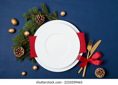 Festive christmas table setting with golden cutlery and porcelain plate and christmas decoration. Mockup for place card, dinner invitation, restaurant menu template. Copy space