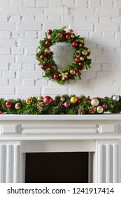 Festive Christmas Wreath Over Fireplace Mantel With White Brick Wall