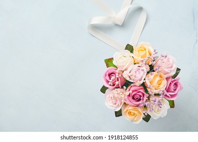 Festive composition with beautiful delicate roses flowers in pink round box on light blue background. Flat lay, copy space. Greeting card.