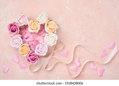 Festive composition with beautiful delicate roses flowers in pink round box on light pink background. Flat lay, copy space. Greeting card.