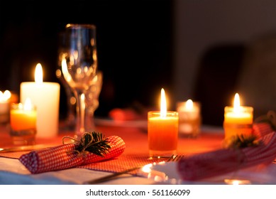 Festive composition with candles and plates. Table decoration. A beautiful table setting, red table cloth, tablecloth in a cage. Christmas dinner. A white plate with a nice napkin on the tabl