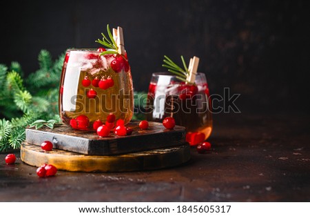 Festive Cranberry and rosemary cocktail with ice on the dark background. Alcoholic or non-alcoholic cocktail.