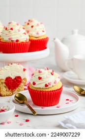 Festive cupcakes with a heart inside for Valentine's Day decorated with sprinkles with hearts on a white plate. Love concept.  Selective focus. - Shutterstock ID 2249007229