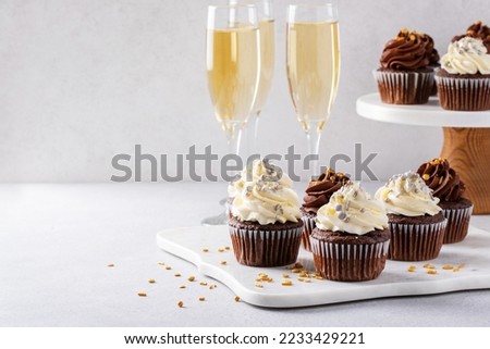 Festive cupcakes with sprinkles served with champagne for New Years Eve party, dessert idea