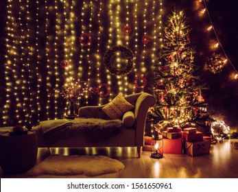 Festive Decorated Home Interior Living Room In With Lot Of String LED Lights, Led Curtains And Pine Cone And Berry Wreaths On Wall, Red Christmas Gifts Under The Tree, Comfortable Canape Sofa Waiting.