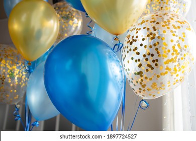 Festive decoration of a bright room with blue and transparent balloons with golden confetti. We celebrate the holidays at home. Interior decoration