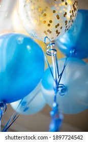 Festive decoration of a bright room with blue and transparent balloons with golden confetti. We celebrate the holidays at home. Interior decoration