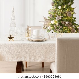 Festive Dining Table Setting, White Dinnerware Set, Crystal, Christmas Theme with Illuminated Tree Adorned with Metallic Decorations and Glistening Star, Golden Accents, Decorative Tablecloth.