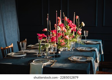 Festive dinner table is served dishes and cutlery and decorated with flowers tulips and greenery, candles. Birthday celebration. Family holidays in modern dining room. Stylish spring party. Wedding. - Powered by Shutterstock