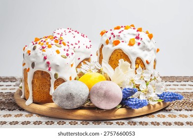 A festive Easter table setting featuring decorated kulich cakes, colorful eggs, and blooming flowers on a traditional embroidered cloth