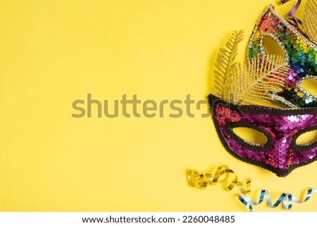 Festive face masks for masquerade or carnival celebration on colored background. Blank greeting card or invitation.