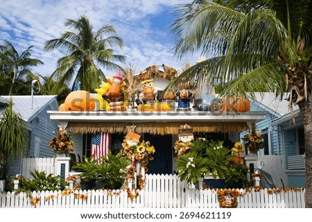 Festive fall scene with pumpkins, scarecrows, and tropical foliage adorning a charming coastal cottage.