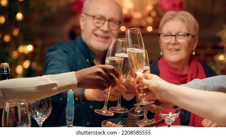 Festive family clinking champagne glasses while enjoying Christmas dinner at home. Happy diverse people celebrating winter feast while drinking sparkling wine together in ornate dining room. - Powered by Shutterstock