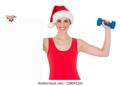 Festive fit brunette holding page and dumbbell on white background