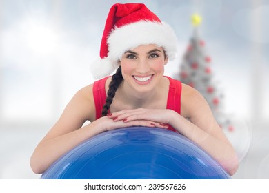 Festive Fit Brunette Leaning On Exercise Ball Against Blurry Christmas Tree In Room