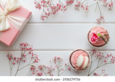 Festive flat lay composition with cupcakes, gift box and pink flowers. Copy space for congratulations. - Powered by Shutterstock