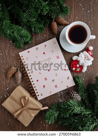 Festive flat lay features a notebook, coffee cup, and holiday decorations on wooden surface