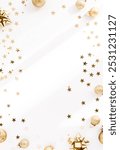 Festive flat-lay arrangement featuring golden Christmas ornaments, glittery baubles, and star-shaped confetti scattered across a light background. Top view. Copy space.