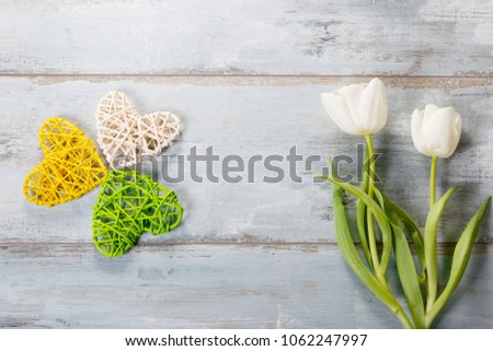 Festive flower white, yellow tulips composition, handmade heart on blue wooden desk, background. Overhead top view, flat lay. Copy space. Birthday, Mother's, Valentines, Women's, Wedding Day concept