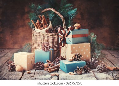 Festive Gifts with Boxes, Coniferous, Basket, Cinnamon, Pine Cones, Walnuts on Wooden Background. Christmas Presents Toned in Vintage Style - Powered by Shutterstock