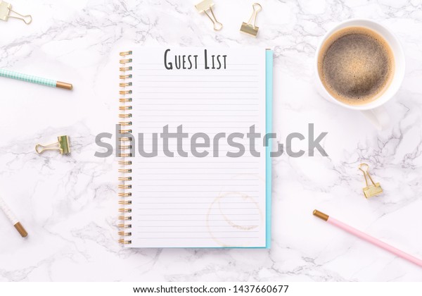 Festive golden stationary and\
coffee on white Guest List wording. Copy space. Top view.\
Horizontal