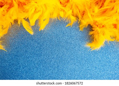 Festive Greeting Card With Bright Yellow Boa Scarf With Fluffy Feathers Lying On Light Blue Sparkling Background With Space For Design Extreme Close View