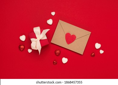 Festive holiday greeting card for Valentines, Birthday, Woman, Mothers Day. Red white hearts, envelope and gift box on red background. Valentines day concept. Flat lay, top view, copy space.