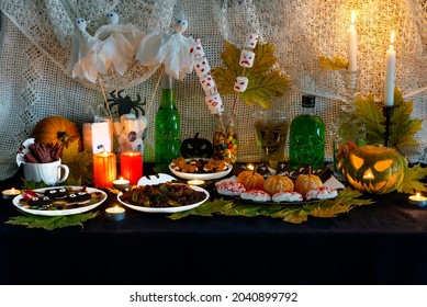 Festive Home Buffet Table With Sweet Snacks And Themed Decorations For Halloween. Halloween Themed Food And Decor. Various Desserts And Decor On Table. Halloween Party Food Corner Table Scene. 