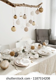 Festive Living Room Decorated For Christmas And New Year With Stylish Table Set For Four Person And Vintage Christmas Decoration Hanging Above It.