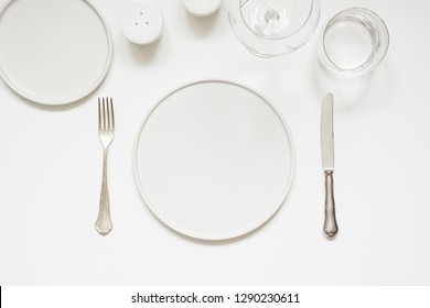 Festive Modern White Table Setting. Plates And Cutlery On White Background. Top View.