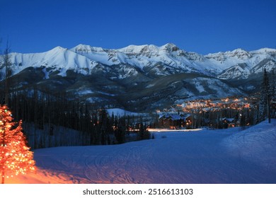 A festive mountain village illuminated by warm holiday lights, nestled below snow-covered peaks. The scene captures the peaceful beauty of a winter wonderland, perfect for holiday and ski adventures. - Powered by Shutterstock