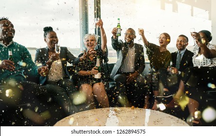 A festive multi ethnic group of people smiling, toasting with sparkling wine and beer. Celebrating the end of the working year and to the new year ahead - Powered by Shutterstock